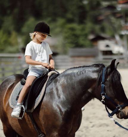 Kind beim Ponyreiten im Familienurlaub in Österreich